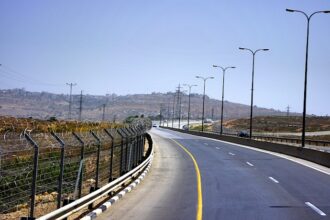 A desolate road in Israel lined with security fencing.