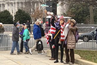 Protesters in Washington DC, the day before the January 6 insurrection, wrapped in American flags blow shofars.