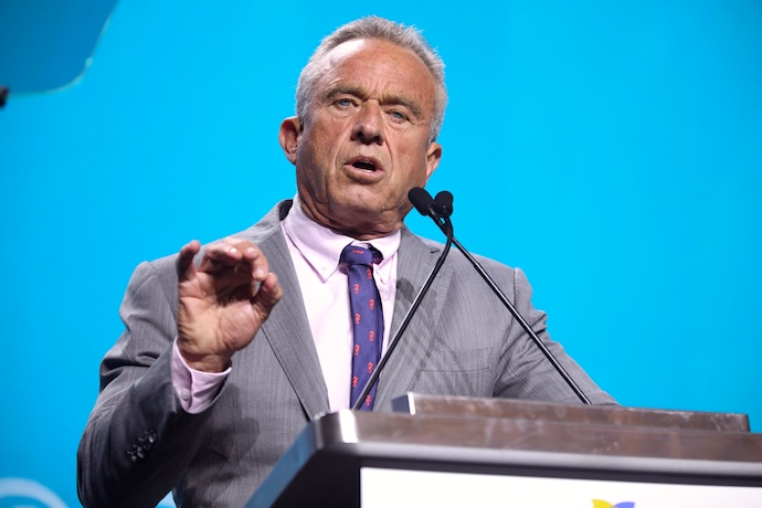 Robert F. Kennedy, Jr. stands at a podium looking directly into the camera with intensity.