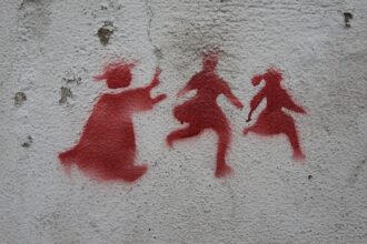 Graffiti on a wall in Lisbon depicting a priest chasing two children, denouncing the child abuse scandal that rocked the catholic church