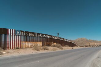 US/Mexican border wall painted with American flag, "no 45" and Klansman